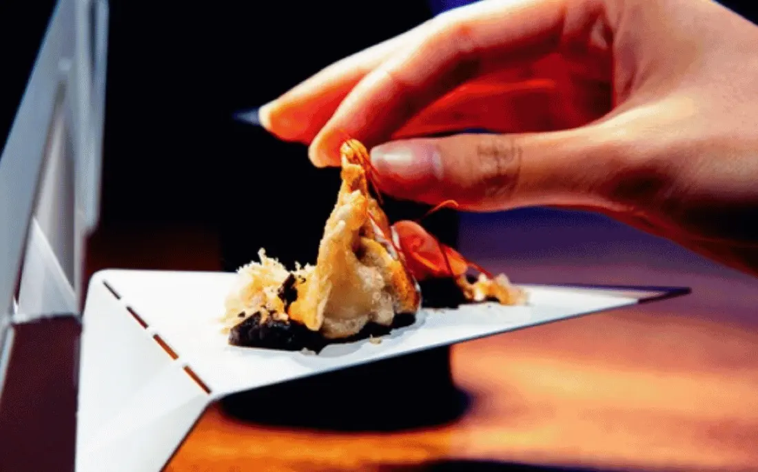 Plato de alta cocina sostenido con la mano